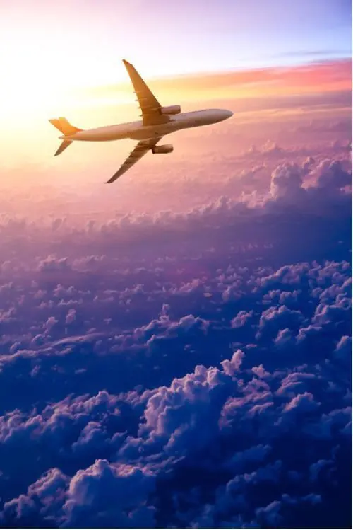 Download Airplane Flying Above Purple Clouds Background