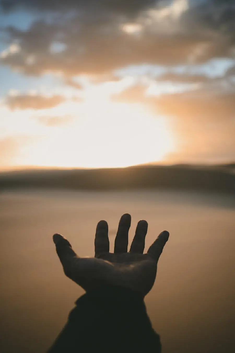 A hand stretched towards the sunset in the desert for a quality mobile background