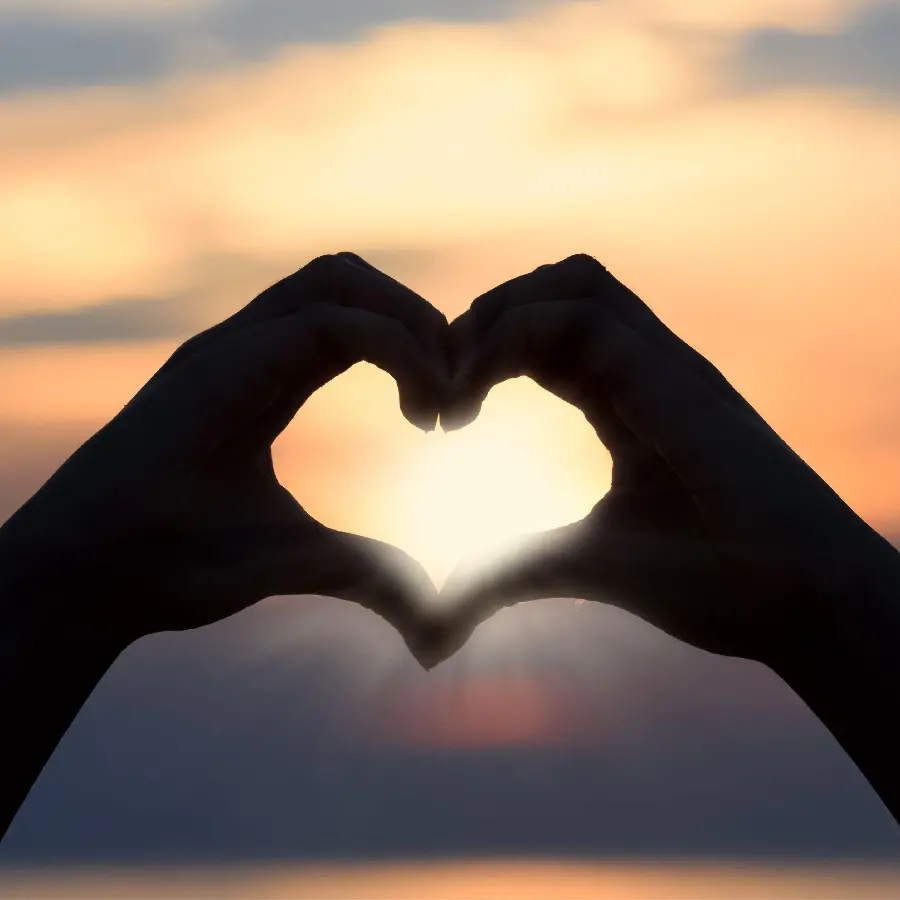 Hands making a heart at sunset for wallpaper
