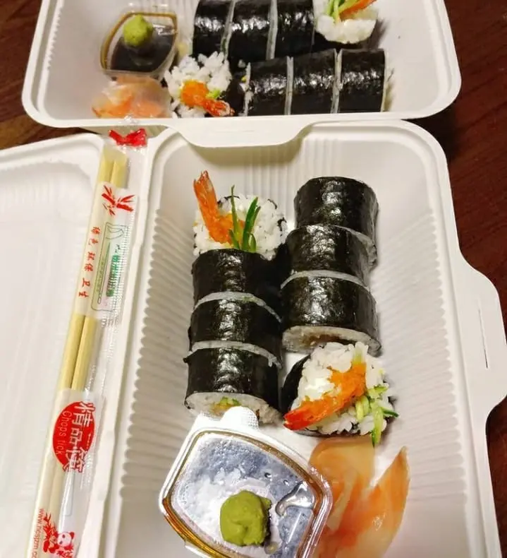 Photo of salmon sushi with seaweed in disposable restaurant container