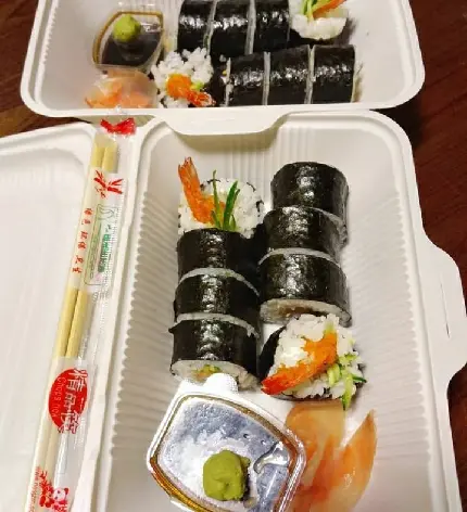 Photo of salmon sushi with seaweed in disposable restaurant container