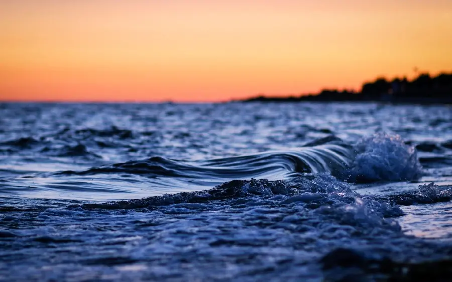 Download the background image of blue ocean waves under an orange sky for laptops and computers