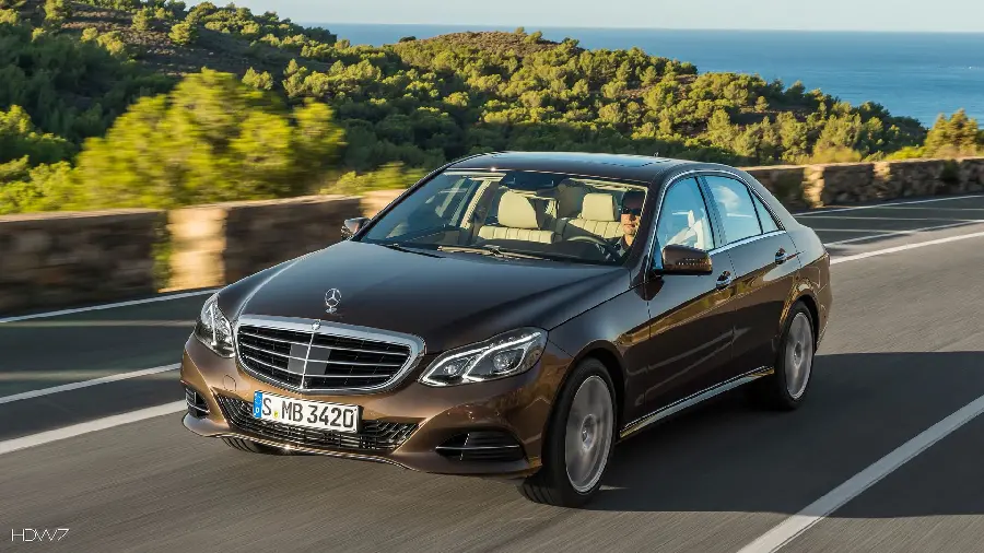 A nice picture of a brown Mercedes-Benz E300 on a coastal road
