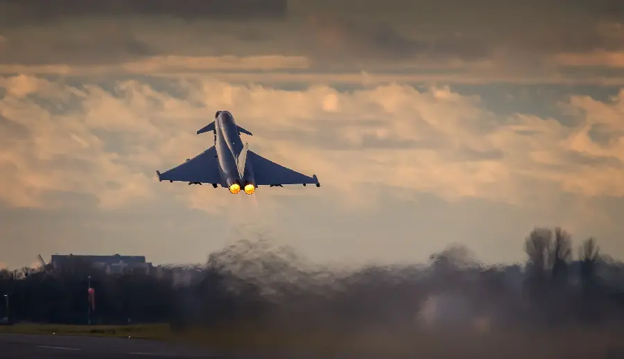 Download an interesting background of a fighter jet flying in a cloudy sunset sky with excellent quality