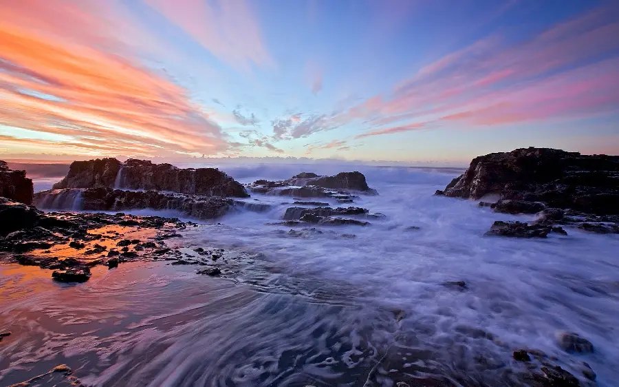 Photo of sea waves in the ocean on the side of large and formidable rocks