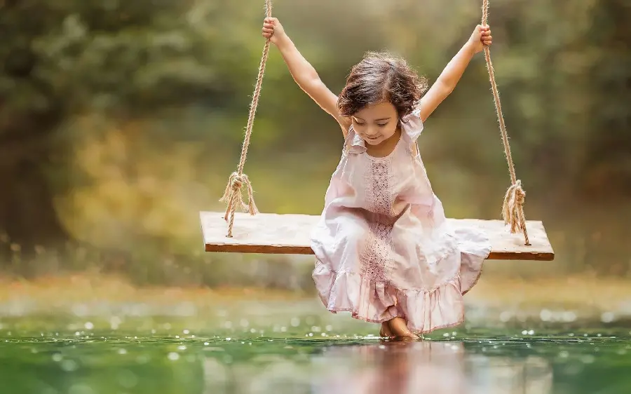 Picture of a beautiful and cute little girl swinging in the lake