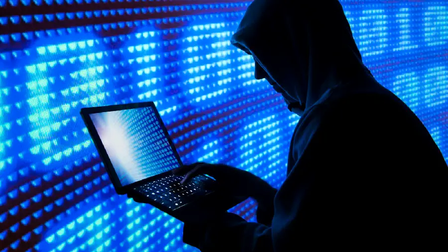 Photo of a hacker man with a laptop in his hand hacking complex systems