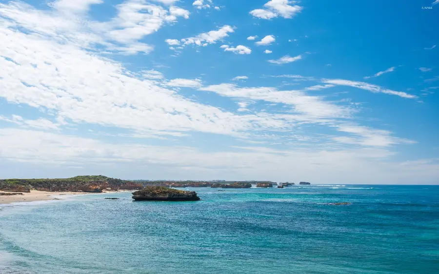 A stunning and relaxing photo of the blue ocean under a cloudy and beautiful sky