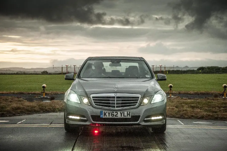 High-quality photo of a silver Mercedes-Benz E300 in cloudy weather in a field