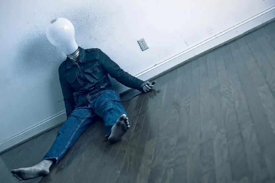 Interesting background with the subject of a human with a bulb-shaped head and unplugged from the power outlet