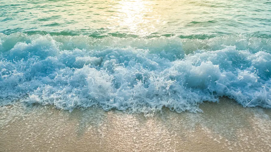 Wallpaper of dreamy ocean waves foaming on the edge of the beach in 8k quality