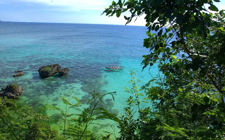 Ocean background photo and next to a small island and a boat in clear water