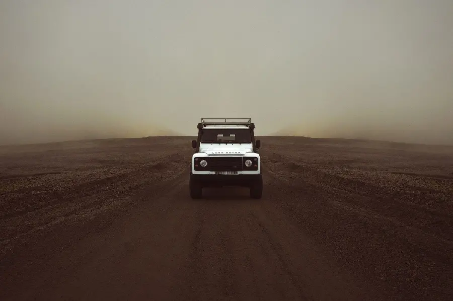 Background photo of a white Land Rover SUV in a desert background