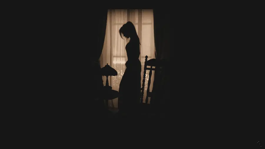 Sad and upset profile photo of a beautiful girl in a room with a black background