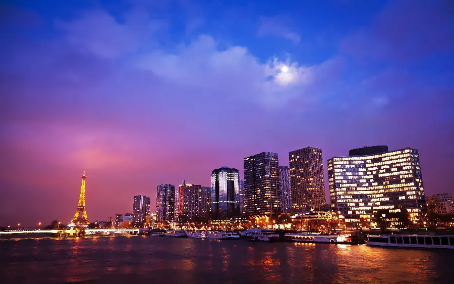 A beautiful background photo of the towers and skyscrapers next to the historic Eiffel Tower, a symbol of the culture of Paris and France at night