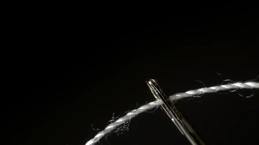 Normal photo of threading a needle on a black background in high quality