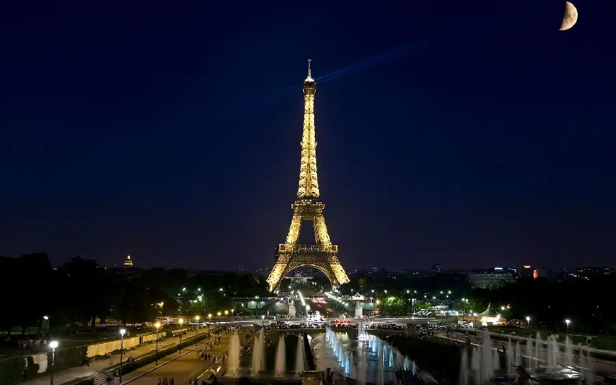 A beautiful stock photo of the Eiffel Tower at night next to the crescent moon in Paris, the cradle of culture, high quality