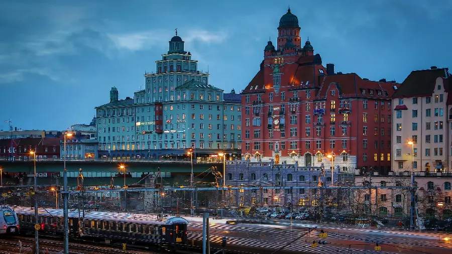 A stunning stock photo of 2 beautiful new blue and red buildings next to a railroad and a commuter train