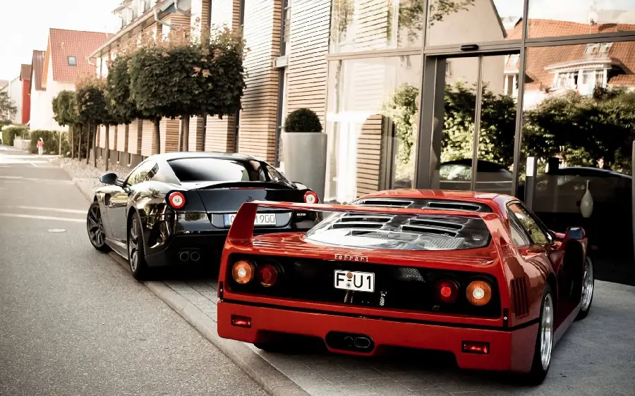 A background image of a patterned and patterned background in front of a glass building of two old and classic Ferraris with strange hoods