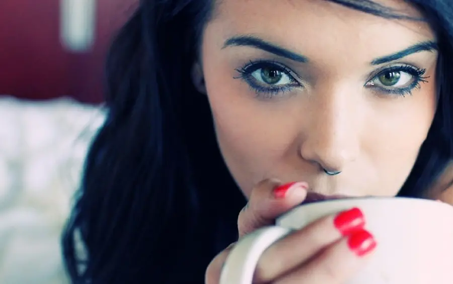A photo of a charming girl with a special look drinking tea