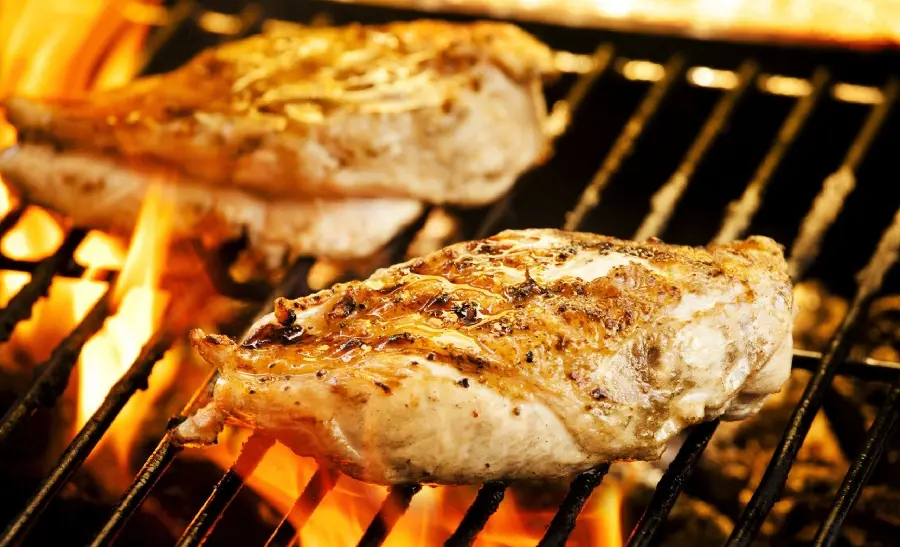 The hottest high quality background of two pieces of spicy grilled chicken on a grill with fire