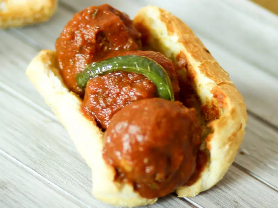 Download the cutest background image of an exciting Kofte dish, three pieces dipped in sauce and a slice of bell pepper inside a baguette for your mobile profile