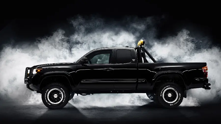 Background with dense clouds of a black Toyota Tacoma with special tires and rims