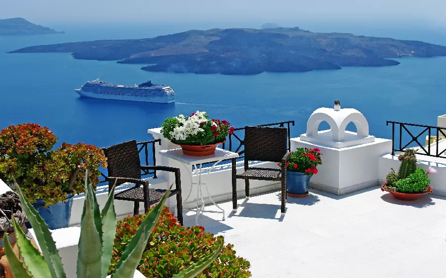 Background of a lush space with beautiful flowers and tables and chairs on the beach of Santorini island