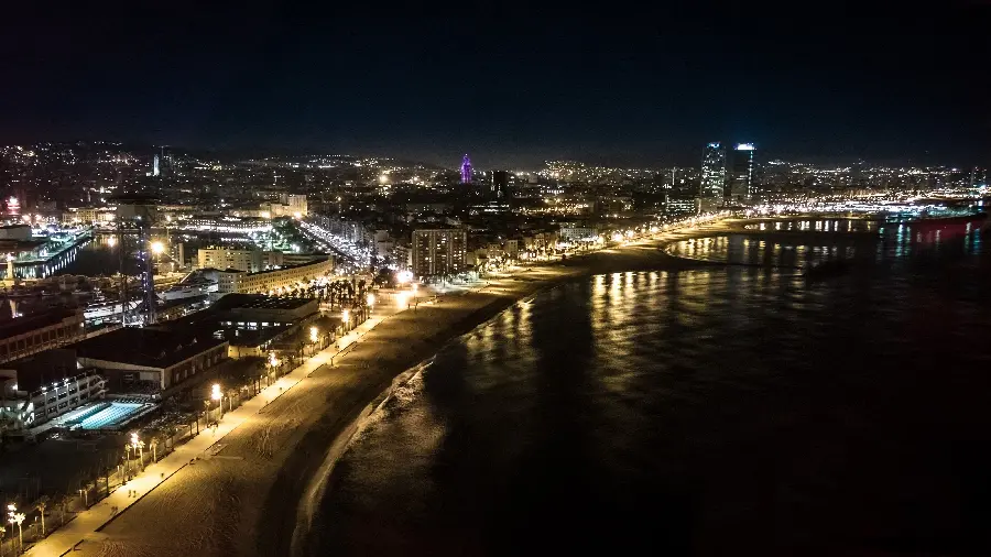 A dark and enjoyable background photo of the view of the Barcelona waterfront and its bright lights at night