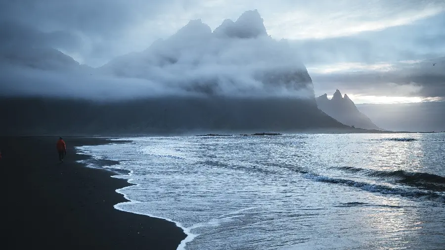 Black and white background photo of the phone from the ocean side with scattered clouds and unknown mountains