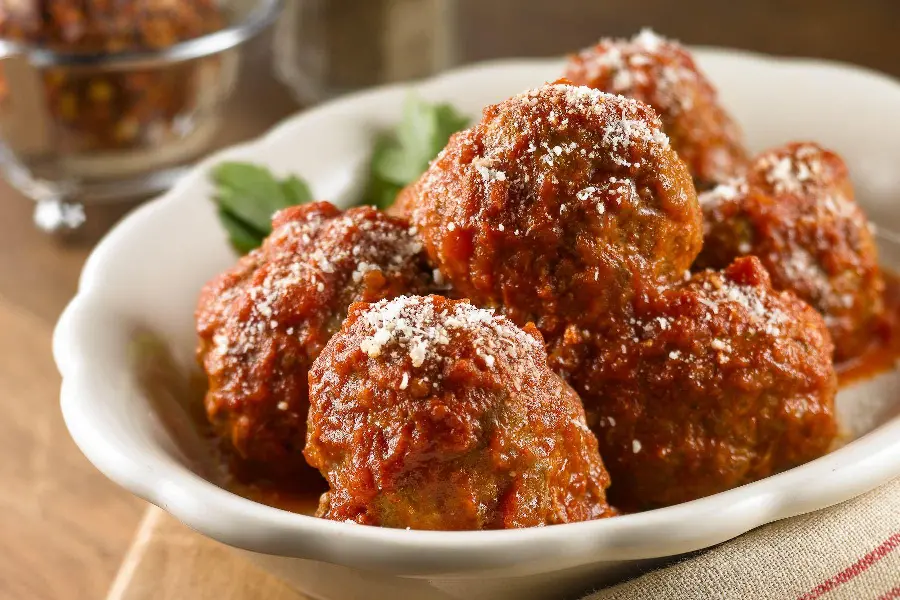Download a unique background photo of a large meatball covered in tomato paste and garnished with parsley on a white plate, suitable for Telegram
