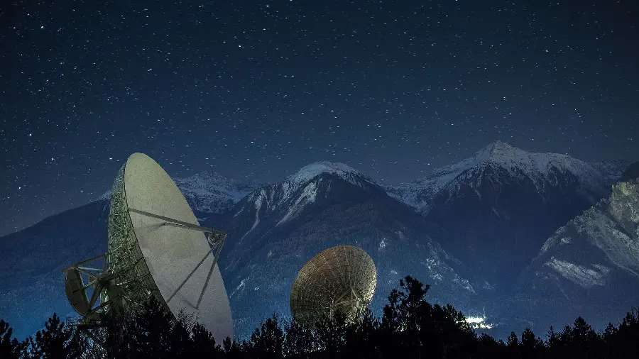 Photo of an extremely large satellite dish under the starry night sky