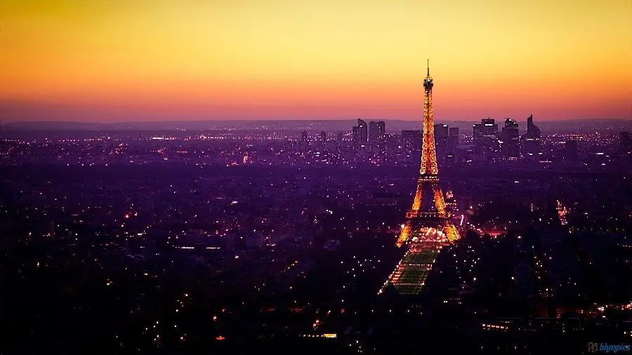 A spectacular photo of the Eiffel Tower at night and the heart of Paris, kindergarten of culture, with an orange and yellow sky, HD quality