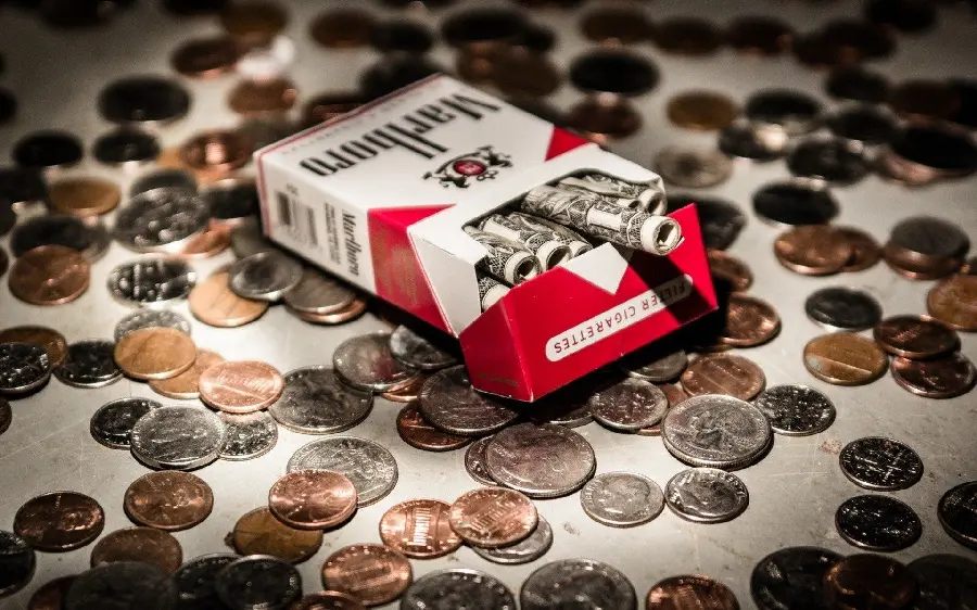 Marlboro cigarette box wallpaper with paper money inside and coins around it