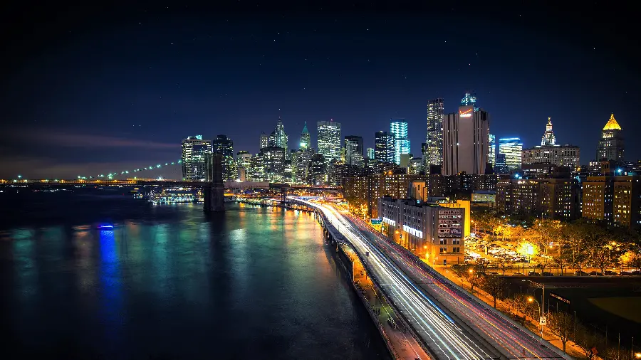 Download a profile photo of a vast city with lots of light at night next to a large river