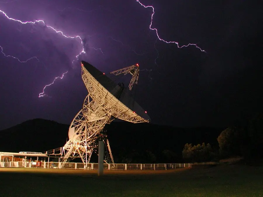 Image of lightning near a huge satellite dish
