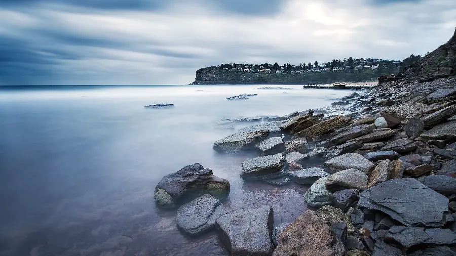 Download a blurred and mysterious background image of the ocean and the mountains and the surrounding stone slabs