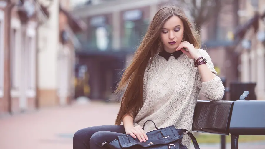 A special and soulful computer background photo of a girl with closed eyes and straight hair and a white dress sitting on a bench