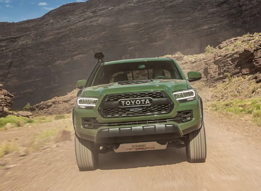Download an energetic background image of a green Toyota Tacoma on a rough mountain road