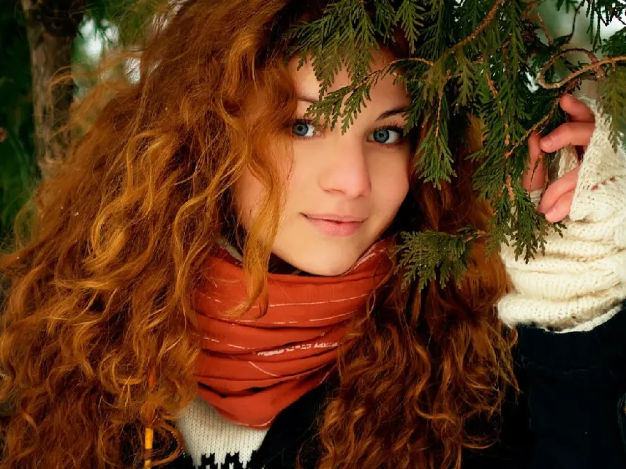 Download artistic stock image Of a cute girl with curly copper hair and an orange scarf among green branches