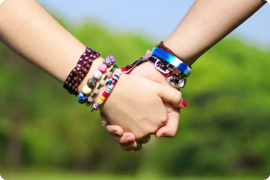 Two friends holding hands with famous friendship bracelets in a beautiful 4K frame