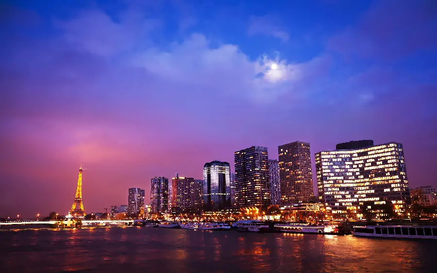 A beautiful background photo of the towers and skyscrapers next to the historic Eiffel Tower, a symbol of the culture of Paris and France at night