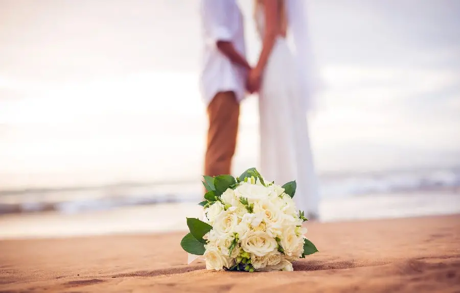 Blurred background photo of bride and groom and bouquet on the beach