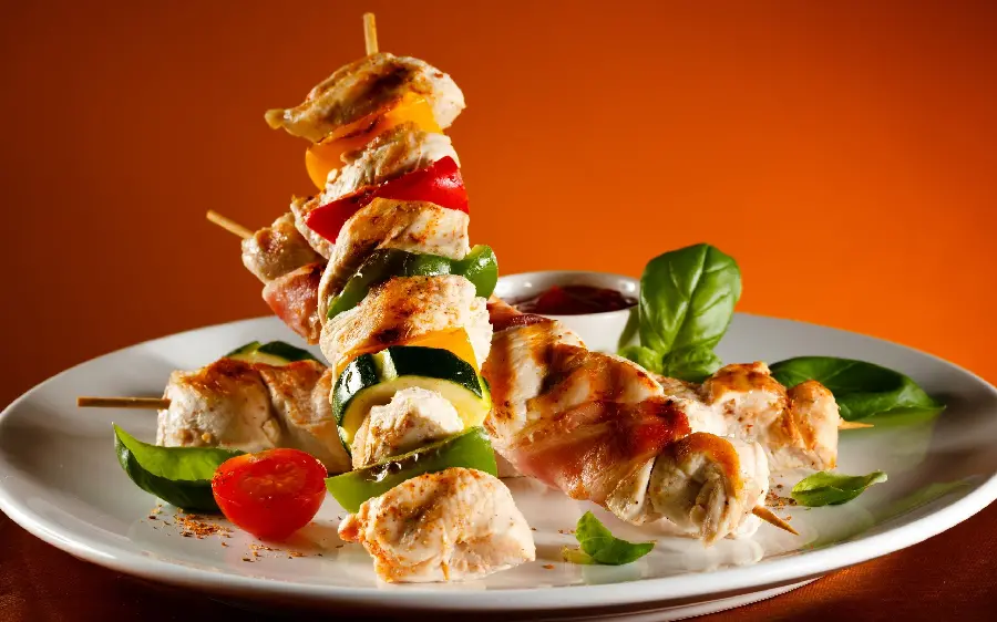 Top background of popular snail chicken fillet kebab with green bell pepper slices and tomatoes on a white plate suitable for Instagram