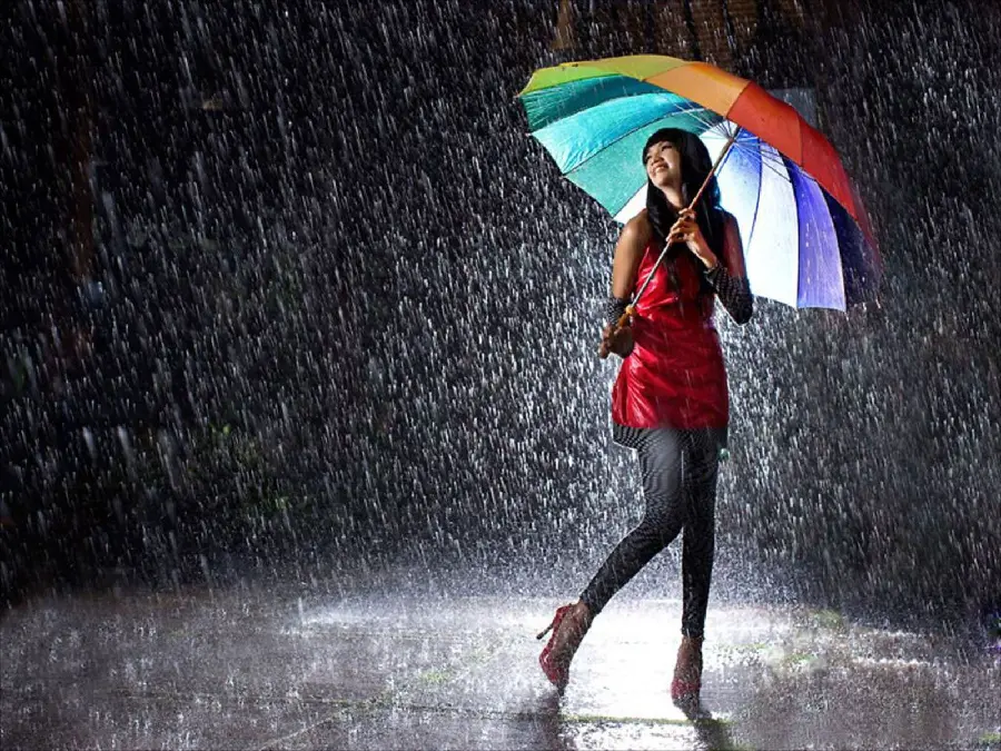 Download luxury wallpaper of a girl A cheerful red dress with a colorful umbrella on her head in real rain