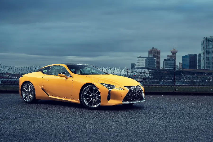 Top background photo of Lexus Yellow LC 500 next to luxury buildings