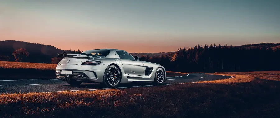 Dark background image of a gray Mercedes-Benz on a forest road