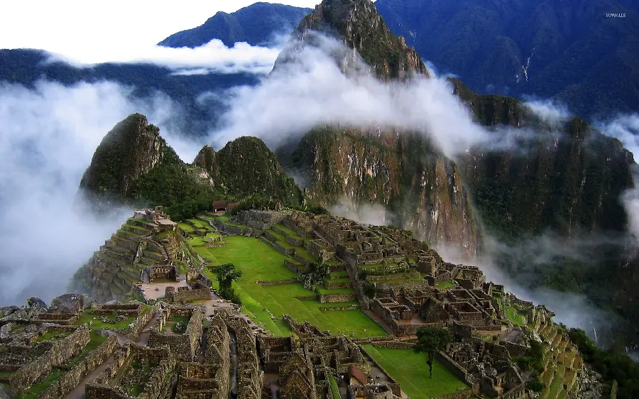 Download the popular background image of the mountain range among the clouds of the city of Machu Picchu