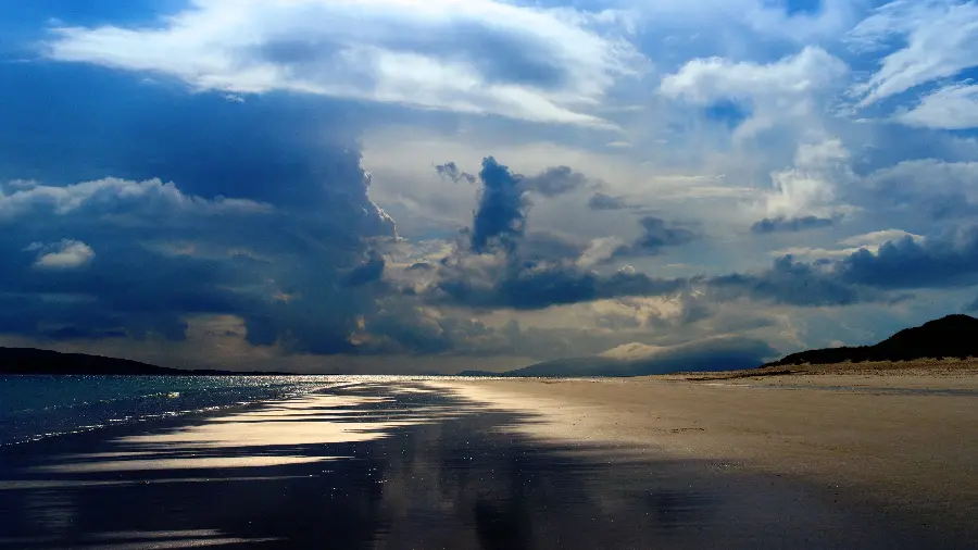 Download photo of dark ocean and a corner of mountains and beach and a sky with scattered clouds