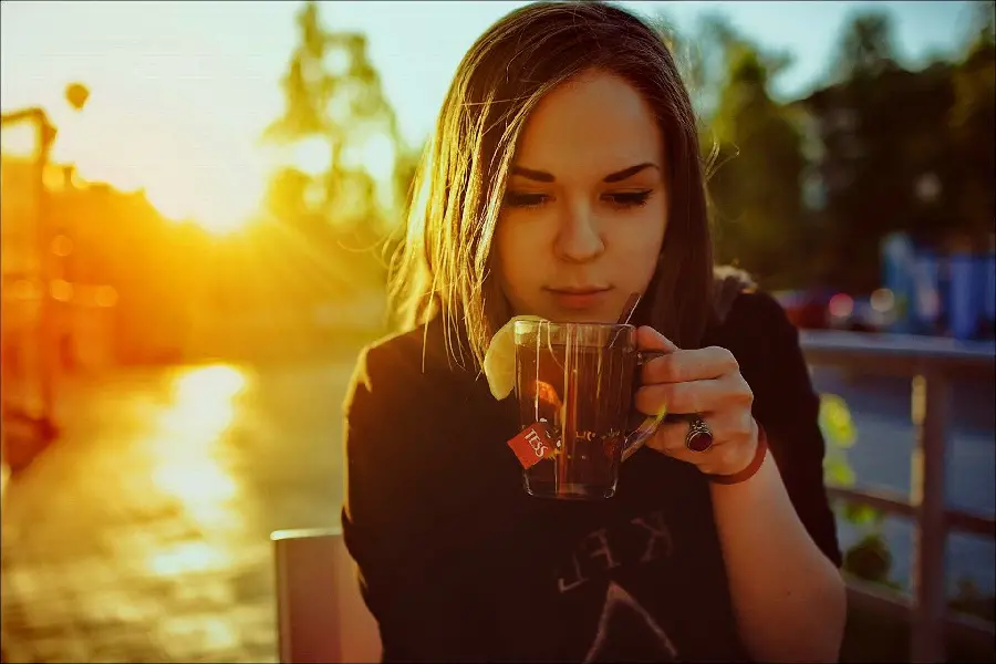 Photo of a girl drinking with a dreamy sunset background